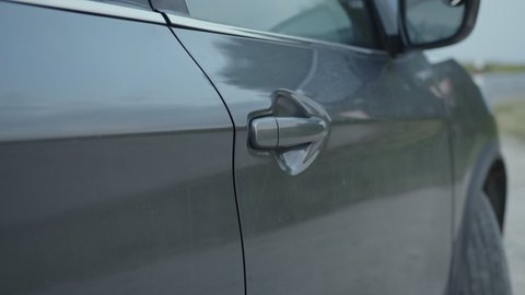 Man can't open his automobile handle door, grey car, human hand