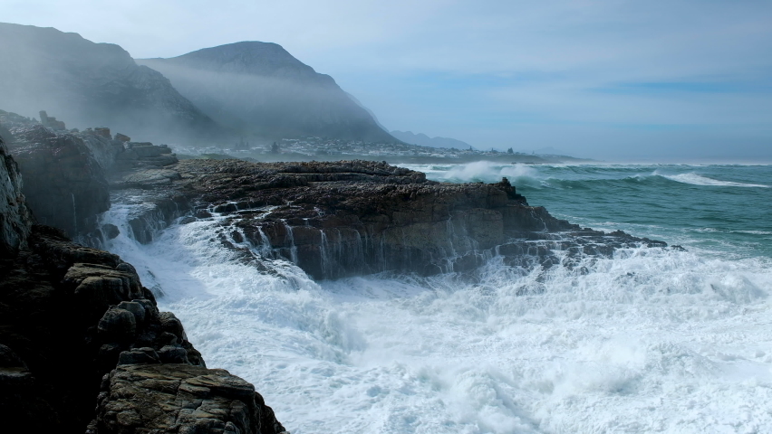 Huge wave making a big splash as it crashes into rocks on rocky coastline, Hermanus Royalty-Free Stock Footage #1076917250