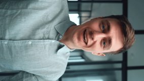 Close-up portrait of smiling young man making selfie or video call while sitting at office in workplace. Vertical orientation video of male blogger doing video chat from modern apartment. - Powered by Shutterstock - Get 15% off with code: PIKWIZARD15