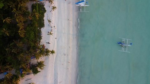 A sandy tropical beach with crystal-blue water, green palm trees, and boats on the shore, a view from above on the paradise white beach, Philippines, Boracay Island, summer and travel vacation concept