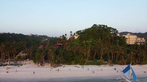 View from above of a sandy tropical white beach green palm trees, luxury hotels, boats on the shore, and tourists walking along the beach, Boracay Philippines sunset on the beach, summer and vacations