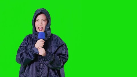 Young asian woman wearing raincote. Green background for chroma key composition.