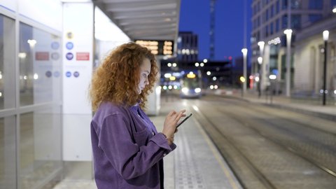 Young woman waiting for train reading text messages