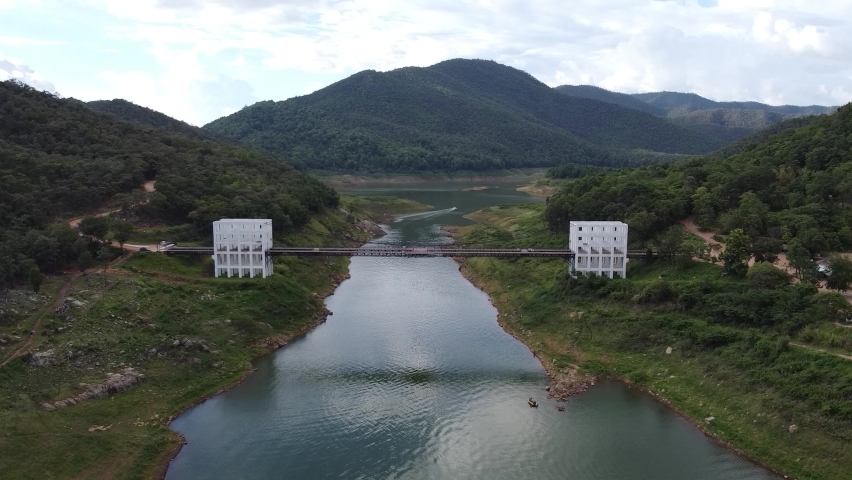 White suspension bridge that surrounds lush mountains aerial view