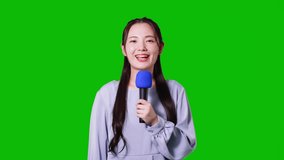 Young asian woman talking with a microphone. TV reporter. Green background for chroma key composition.