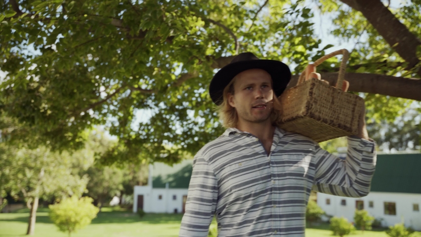 Caucasian male walking through village carrying vegetable basket on shoulers