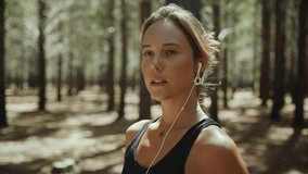 Caucasian female running in forest listening to music with earphones