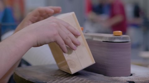 Super slow motion: professional man carpenter using belt sander machine, polishing wood product at workshop - close up. Design, handmade, woodwork, carpentry, craftsmanship, manufacturing concept