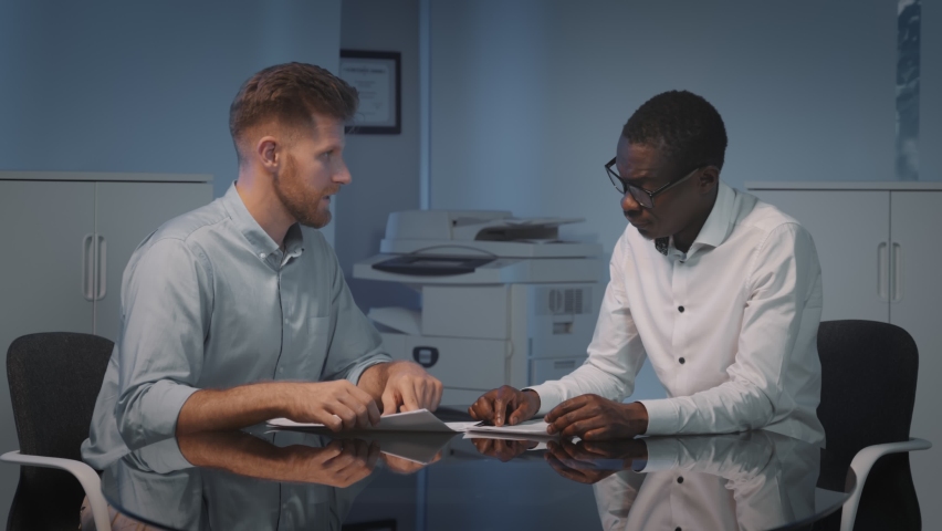 Multiethnic business partners handshaking after deal or interview. Caucasian manager consulting african client and shaking hands in agreement sitting at table in modern office Royalty-Free Stock Footage #1076962016