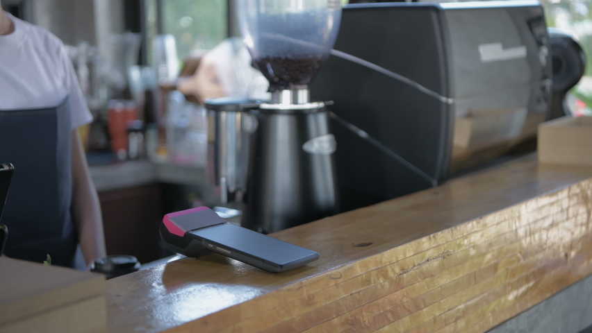 Coffee shop concept of 4k Resolution. The employee is handing the payment machine to the customer for scanning.