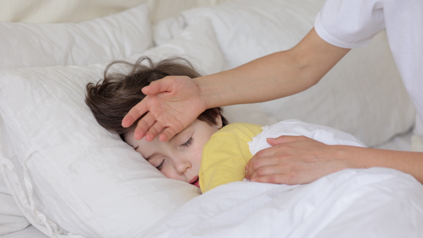 Worried parent call doctor nervous of child fever. Mom touch hot forehead of sleeping boy make phone call to pediatrician. Caring mum treating sick kid at home. Family healthcare and health concept | Shutterstock HD Video #1076973119