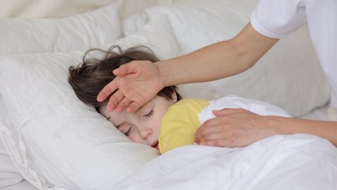 Worried parent call doctor nervous of child fever. Mom touch hot forehead of sleeping boy make phone call to pediatrician. Caring mum treating sick kid at home. Family healthcare and health concept