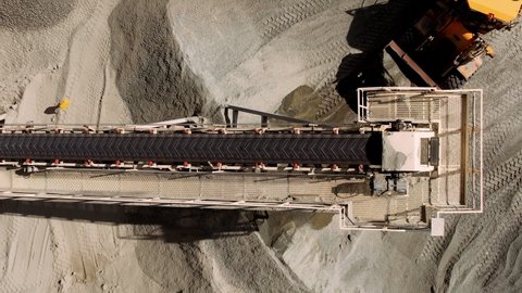 Aerial top down of coal conveyor belt piling up coal at a depot. Fossil fuel reliance, sustainability and global warming concepts. Quarry, opencast mining, ore extraction concept.