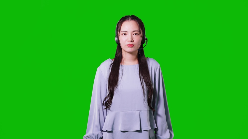 Young asian woman talking with headset. TV reporter. Green background for chroma key composition. Royalty-Free Stock Footage #1076978312