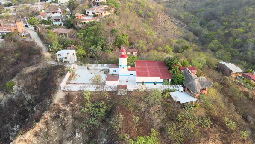 Orbital plane to left with jib up, around small lighthouse, with view of cliff at sunrise in Oaxaca