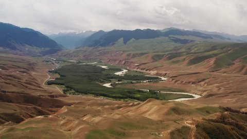 Mountain peaks and grassland are under white clouds. Aerial photograph in Kuokesu gorge, Xinjiang, China.