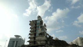 A bulldozer is busy crushing and demolishing an old building in an urban environment. a 4K video clip, Tel Aviv, Israel.