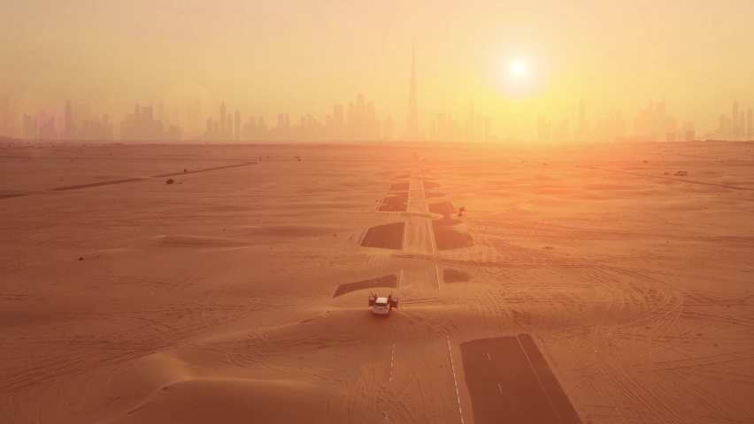 Aerial shot. Couple in the car, stands on the road after sandstorm. Silhouette Dubai city at the sunset. | Shutterstock HD Video #1076994425