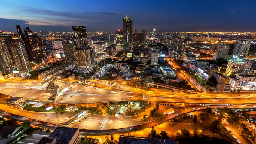 Time lapse of aerial view of busy cars with traffic jam in the rush hour on highway road street on bridge in Bangkok Downtown, urban city, Thailand at night. Intersection junction. Toll gate in Rama 9
