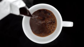 Hot black coffee. pour black coffee in white cup on black background, top view. 4K UHD video