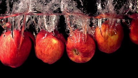 Super slow motion fresh apples fall under the water with splashes. On a black background.Filmed on a high-speed camera at 1000 fps. High quality FullHD footage