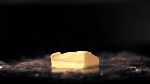 Super slow motion a piece of butter in a frying pan melts with hot steam. On a black background.Filmed on a high-speed camera at 1000 fps. High quality FullHD footage