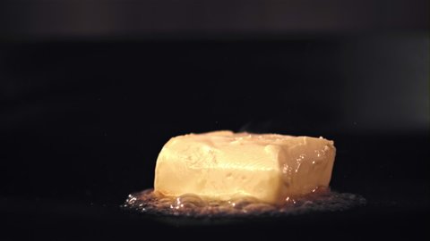 Super slow motion in the pan melts a piece of butter. On a black background. Filmed on a high-speed camera at 1000 fps. High quality FullHD footage