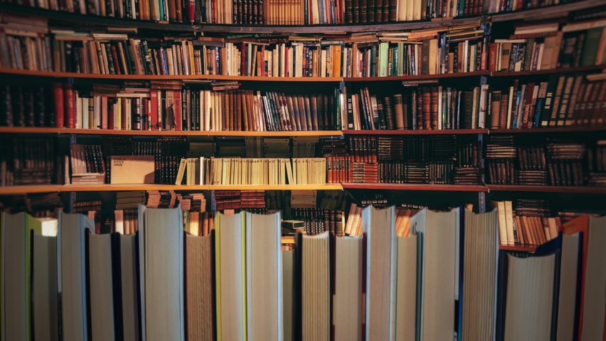 Library Bookshelves Background Stack of Books Camera Movement. Camera moving in front of a stack of books inside a big library. Background