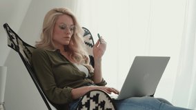 Young woman using laptop and electronic cigarette while relaxing at home 