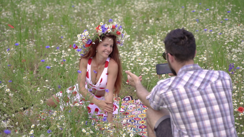 The guy takes a picture of a woman on a cell phone.