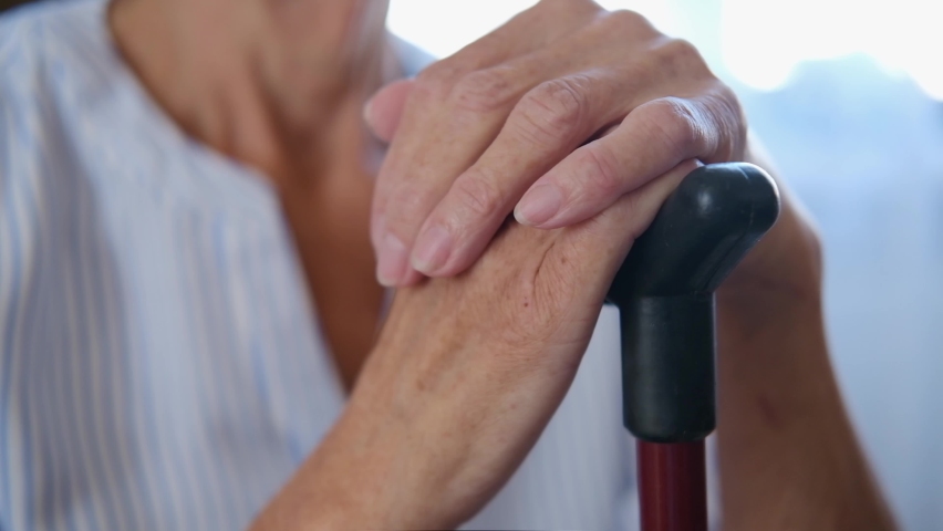 Caucasian old senior grandmother holding walking cane stick in hands. old wrinkled hands of a grandmother with a cane close-up. loneliness concept in old age.pain in joints of the hands. osteoporosis. | Shutterstock HD Video #1077004220