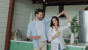 Beautiful young couple smiling and dancing while spending time in the kitchen