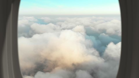 View from passenger plane window of a scene with thick white clouds over the city landscape, evening cinematic view