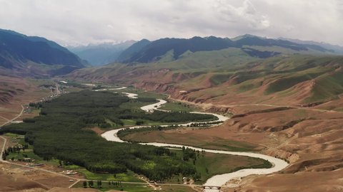 Mountain peaks and grassland are under white clouds. Aerial photograph in Kuokesu gorge, Xinjiang, China.