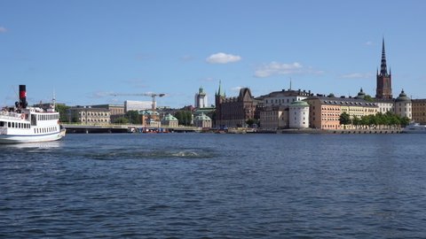Stockholm, Sweden, 08.04.2021: Transport boat or ship runs between the islands on Lake Malaren. View Riddarholmen with towers and beautiful buildings. Famous landmarks of Sweden. Stockholm Panorama.