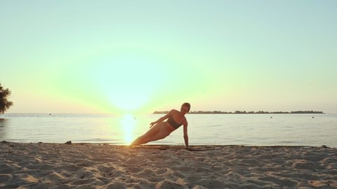 barre workout. stretching outdoors. yoga beach. Athletic young woman is doing exercises on mat, at the beach during sunset or sunrise. Fitness training outdoors. Fitness, ballet, sport, yoga and