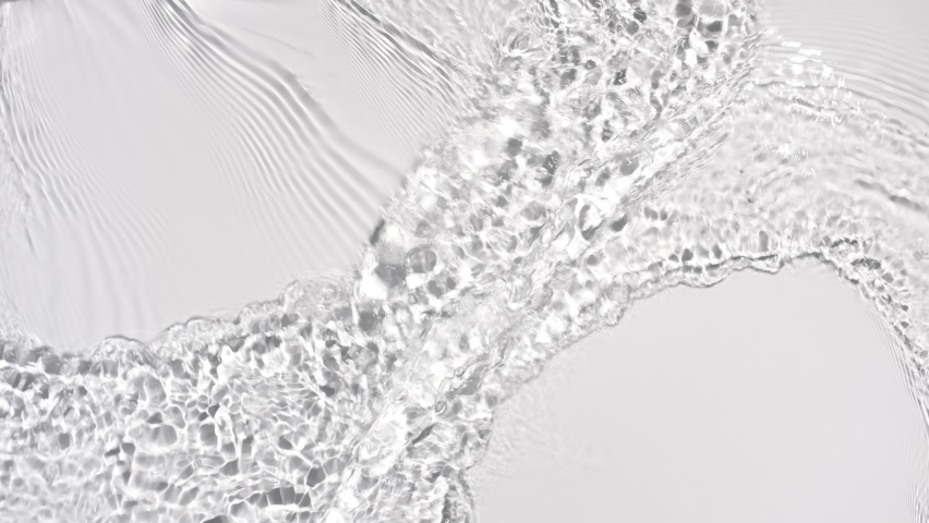 Water flows from opposite sides creating waves, ripples and concentric circles on pale grey background | Background shot for skin care cosmetics with hyaluronic acid commercial | Shutterstock HD Video #1077025610