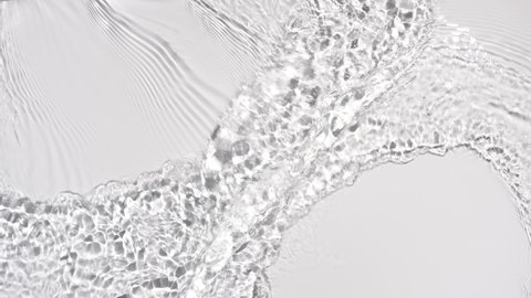 Water flows from opposite sides creating waves, ripples and concentric circles on pale grey background | Background shot for skin care cosmetics with hyaluronic acid commercial