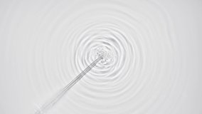 Liquid is injected from syringe creating bubbles and circles on water surface on pale grey background | Macro shot of skin care cosmetics ingredients for its commercial - Powered by Shutterstock - Get 15% off with code: PIKWIZARD15