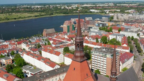Panoramic aerial view of town and surrounding water surface. Orbit shot around top of church tower