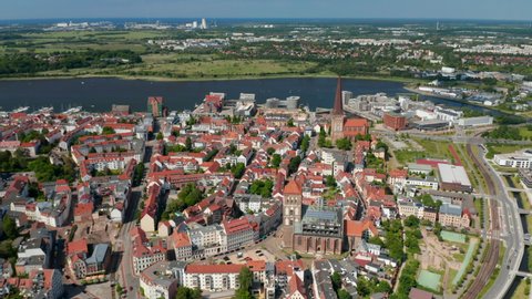 Fly above historic town centre next to sea bay. aerial panoramic view of streets lined by buildings with red tiled roofs