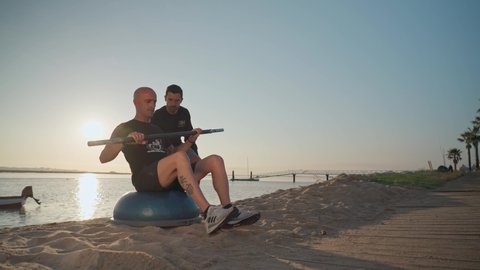 An athlete on the beach, trains in canoeing and receives instructions from a personal fitness trainer. On the bosu ball. Portugal Faro 2021 March 15 