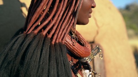 Himba woman in traditional village in Namibia, Africa, slow motion shot. Himba women are famous for their use of otjize, a paste of butter, fat and red ochre, which they apply to their hair and skin.