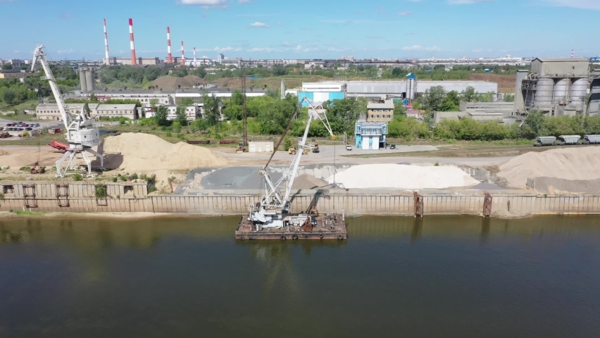 River port. Aerial photography along the shore of the river port with port cranes with special equipment and water transport in the river port. 