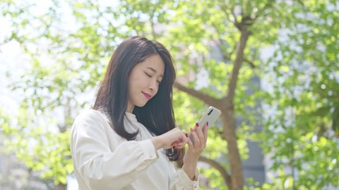 Young asian woman using a smart phone in the town.