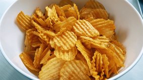 Close-up view of wavy potato chips bowl. Concept of eating junk food, unhealthy eating. 