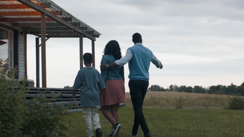 TRACKING Real estate agent showing African American family of three, husband wife and son, a beautiful country house. Shot with 2x anamorphic lens Royalty-Free Stock Footage #1077060320
