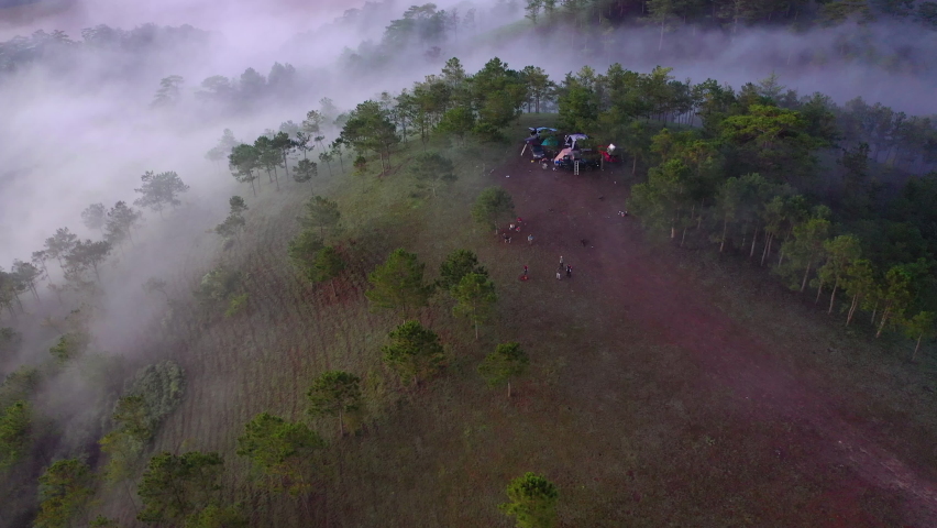Panoramic view, foggy morning and amazing clouds sky. Aerial view of group camping enjoying nature on the hills. Adventure travel with car 4x4 and roof top tent. Beautiful landscape with cloud, fog
