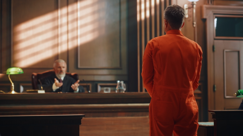 Court of Law and Justice Trial Proceedings: Law Offender in Orange Jumpsuit is Questioned and Giving Testimony to Judge, Jury. Criminal Denying Charges, Pleading, Inmate Denied Parole. Royalty-Free Stock Footage #1077064682