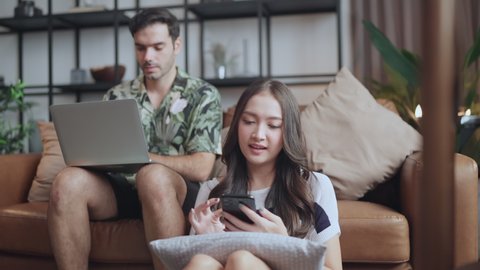 home isolate quarantine,asian and caucasian marry couple sit relax using laptop and tablet social media or shopping online surfing in living room home interior background